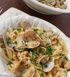 pasta with clams and parsley in a white bowl on a wooden table top