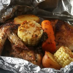 chicken, carrots and corn on the cob wrapped in aluminum foil with potatoes