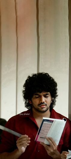 a man with curly hair is reading a book