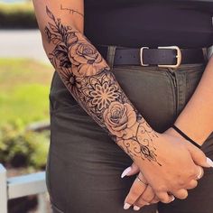 a woman's arm with flowers on it and a black belt around her waist