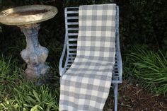 a chair with a towel on it next to a birdbath in the grass