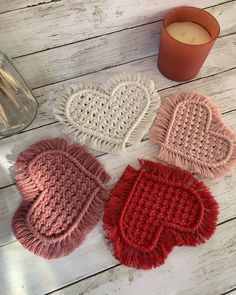 three knitted mittens next to a candle