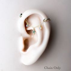 the ear is made out of white ceramic with green and gold beads on each side