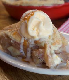 a piece of pie with ice cream on top sitting on a white plate next to a red and white checkered tablecloth