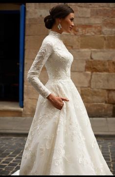 a woman in a white wedding dress is standing on the street with her hand on her hip