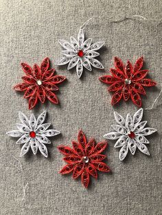 four red and white snowflakes on a gray surface with some thread in the middle