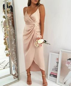 a woman standing in front of a mirror wearing a dress and holding a flower bouquet