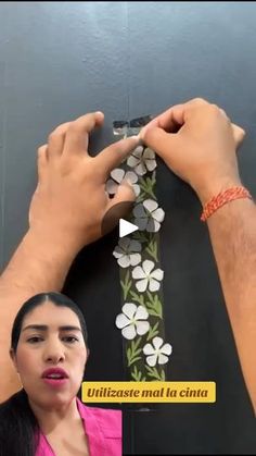 a man and woman standing next to each other with flowers on the wall behind them