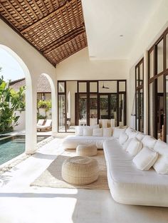 a large white couch sitting in front of a living room next to a swimming pool