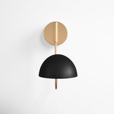 a black and gold wall light on a white wall next to a round object in the shape of a ball