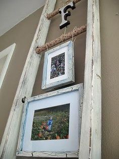 an old ladder is hanging on the wall next to two framed pictures and a rope