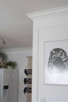 a white refrigerator freezer sitting inside of a kitchen next to a painting on the wall