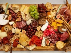 a wooden platter filled with cheese, meats and crackers