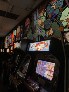 video game machines lined up in front of a wall with teenage mutants on them