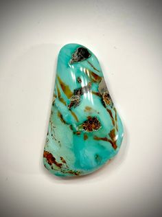 a piece of turquoise colored stone sitting on top of a white table