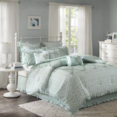 a bed with blue comforters and pillows in a bedroom next to a window,