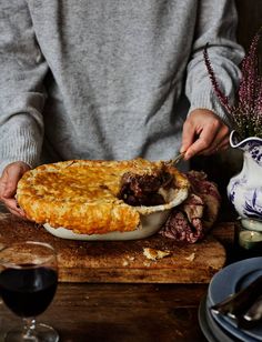 a person cutting into a pie on top of a wooden table