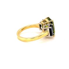 A beautiful pairing of bright colors and sleek shapes form this modern version of a classic 3-stone ring. This stylish ring features a gorgeous, 5.12 carat emerald-cut peridot flanked on either side by emerald-cut rich blue sapphires. The peridot has been set in yellow gold to highlight its warm color, while the blue sapphires have been set in striking white gold, creating a lovely, eye-catching contrast. So pretty and wearable! Handcrafted in 18k white and yellow gold by our Master Jewelers in 3 Stone Rings, Stylish Rings, Shape And Form, Stone Ring, Cocktail Rings, Emerald Cut, Warm Colors, Blue Sapphire, Bright Colors