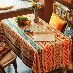 the table is covered with an orange and blue patterned cloth, which has been placed on top of a wooden chair