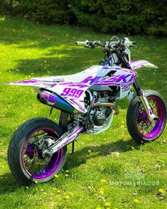 a pink and purple dirt bike parked in the grass