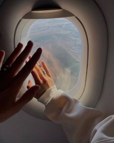 a person reaching out an airplane window to touch the hand of another person's arm