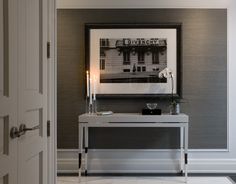 an entry way with a white table and two candles on the end tables in front of it