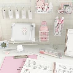 a white desk topped with lots of notebooks and stationary items on top of it