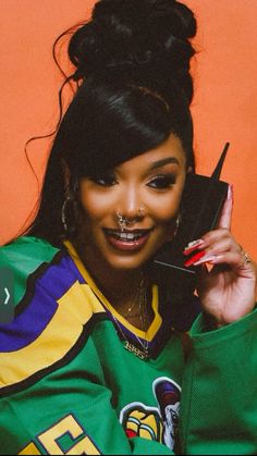 a woman holding a cell phone up to her ear and wearing a green jacket with colorful stripes on it