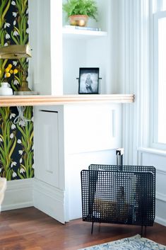 a living room with white walls and wooden flooring next to a shelf filled with plants