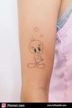 a woman's arm with a small cartoon cat tattoo on the left side of her arm