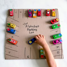 a child's hand writing on a cardboard parking lot