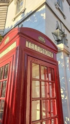 a red telephone booth sitting in front of a tall building