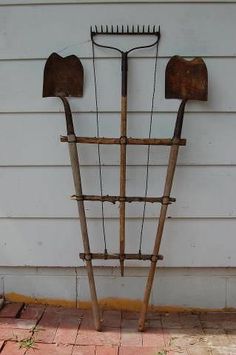 an old garden tool rack with two shovels on it's sides and three forks attached to the back