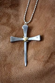 a silver cross on a brown blanket with a ball chain attached to the back of it