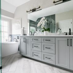 a bathroom with a tub, sink and large mirror