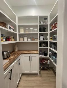 a kitchen with white cabinets and wooden counter tops in the middle of it's shelves