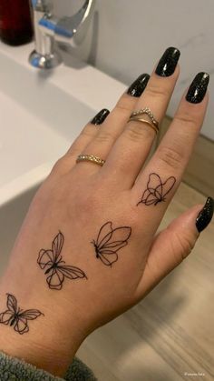 a woman's hand with tattoos on it and a butterfly tattoo on the ring finger