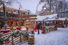 people are walking around in the snow at an amusement park with christmas decorations on display