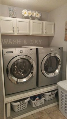 a washer and dryer sitting in a laundry room next to some white cabinets