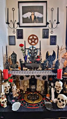 a table topped with skulls and candles next to pictures on the wall above it,