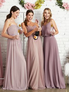 three women in long dresses holding wine glasses