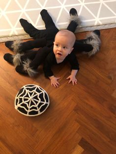 a baby is laying on the floor next to a spider web decoration with his hands