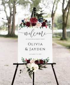 a welcome sign with flowers and greenery on it