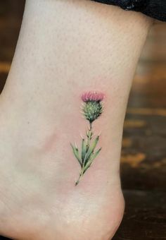 a small pink flower on the ankle with green leaves and petals in it's center