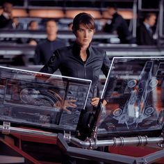 a woman standing next to two laptops in a room filled with other computer equipment