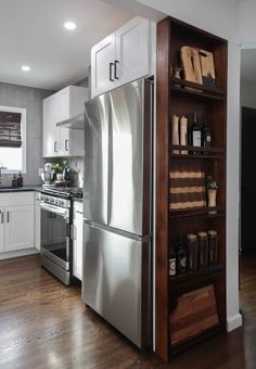 a kitchen with white cabinets and stainless steel refrigerator freezer combo in the corner, next to an open book shelf filled with books