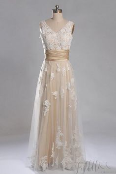 a dress on a mannequin with white flowers and gold ribbon around the waist