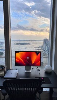 a desktop computer sitting on top of a desk in front of a window overlooking the ocean