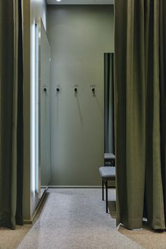 an open door leading to a bathroom with green curtains on the window sill and a chair in front of it