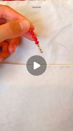 someone is making beaded necklaces on a white piece of fabric with red beads